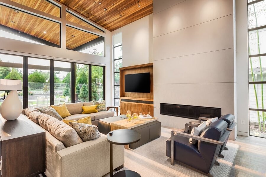 An open living space featuring a family room seating area, a mounted TV, and large windows on the walls surrounding it.